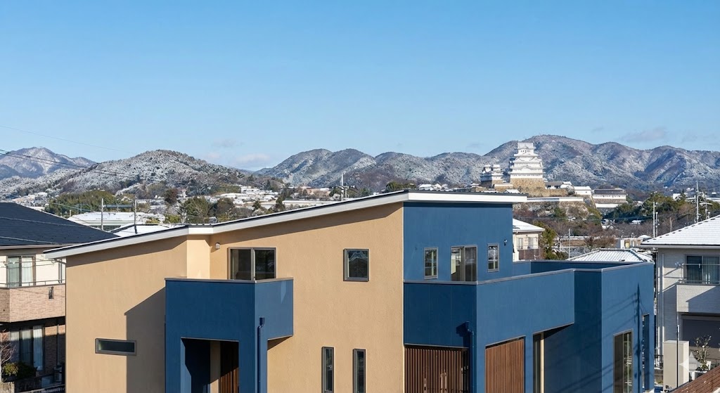 姫路市の青空の下、美しく外壁塗装された住宅。遠くの山にはうっすらと雪化粧が見える冬の景色。