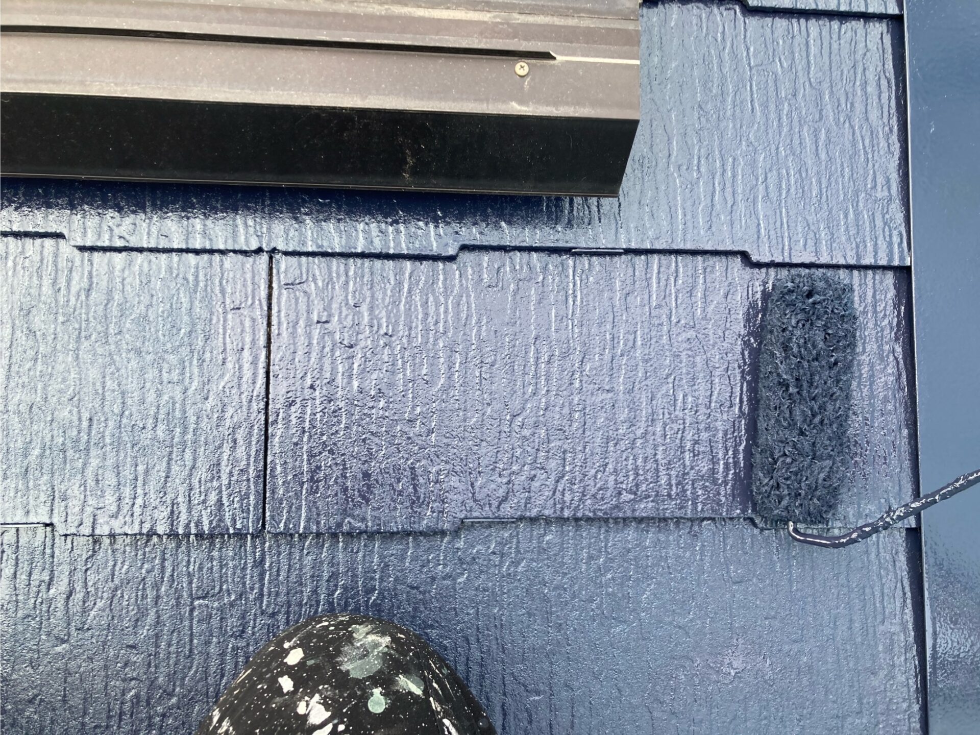 一般戸建て住宅の屋根の上塗りをする様子